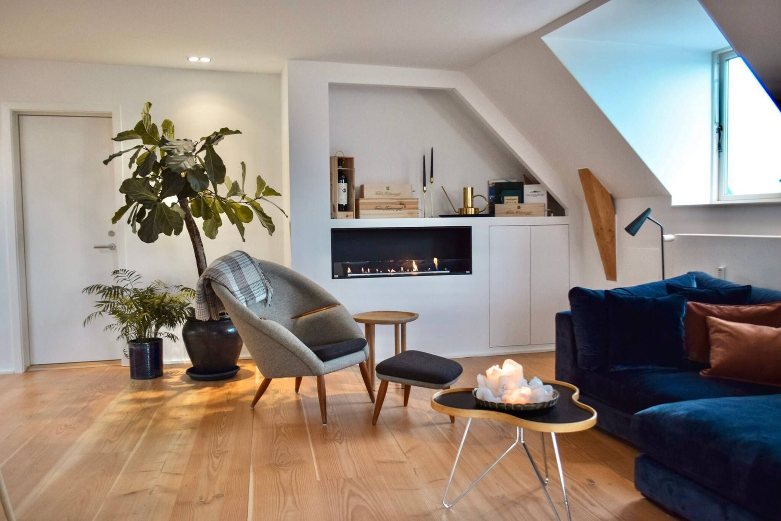 Living room with linear fireplace, lounge chair and velvet sofa